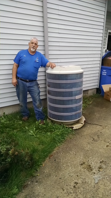 J & L Mechanical technician inspecting a classic round air conditioning condenser system unit